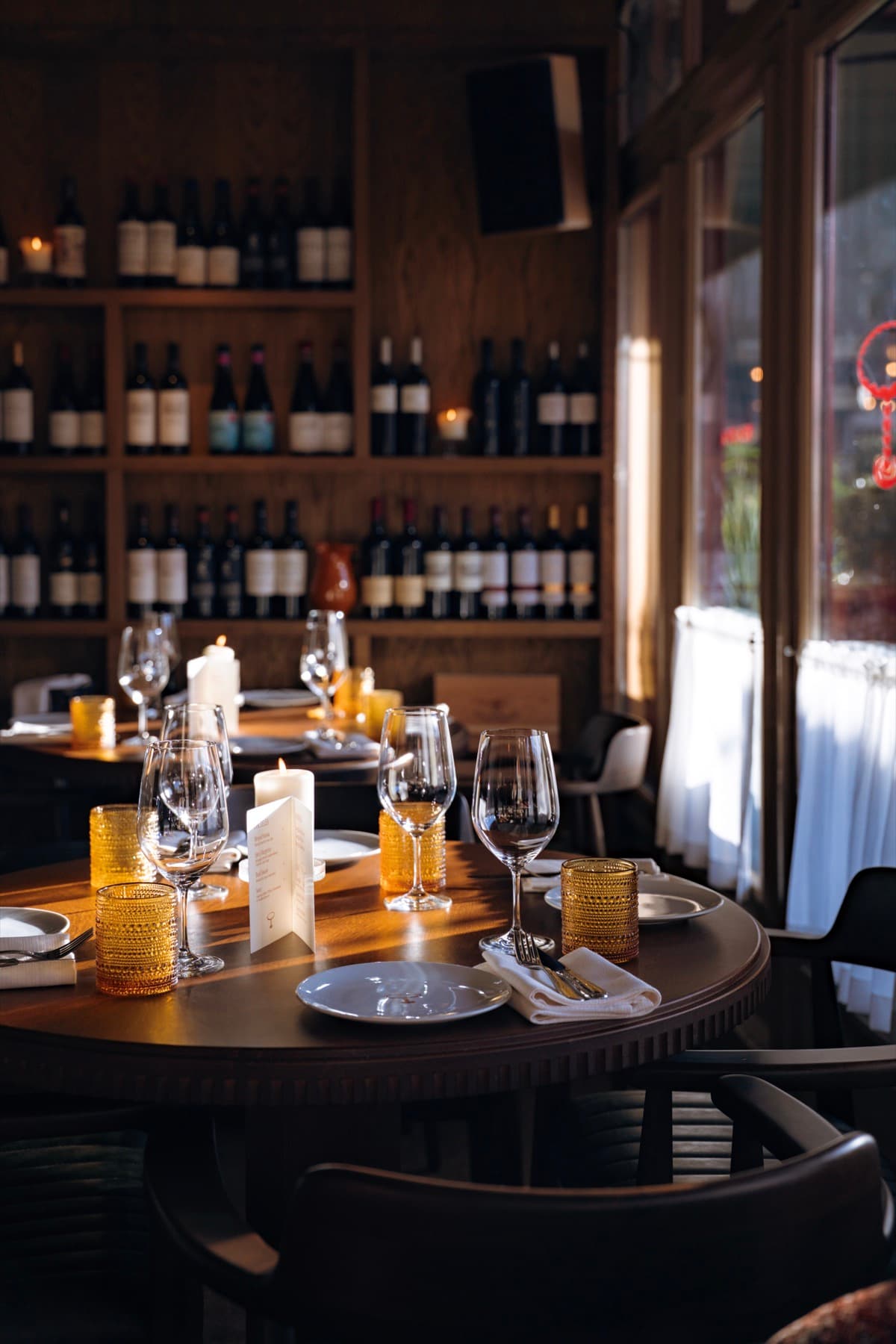 A round table in front of the wine wall